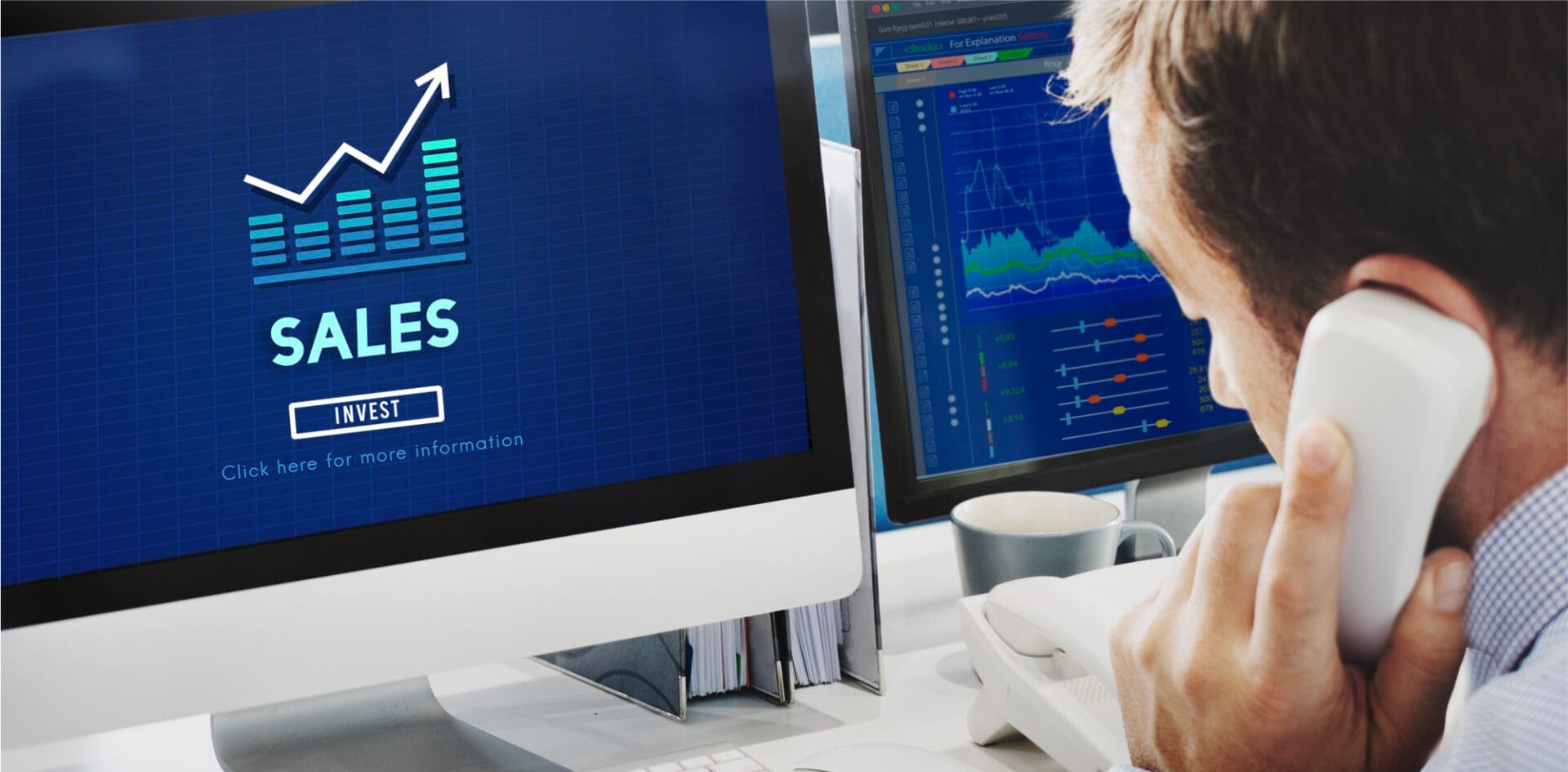 The image depicts a businessman analyzing financial data on two computer screens. One screen displays a sales graph emphasizing growth, while the other shows complex stock market trends, reflecting a professional setting focused on financial investments and market analysis.