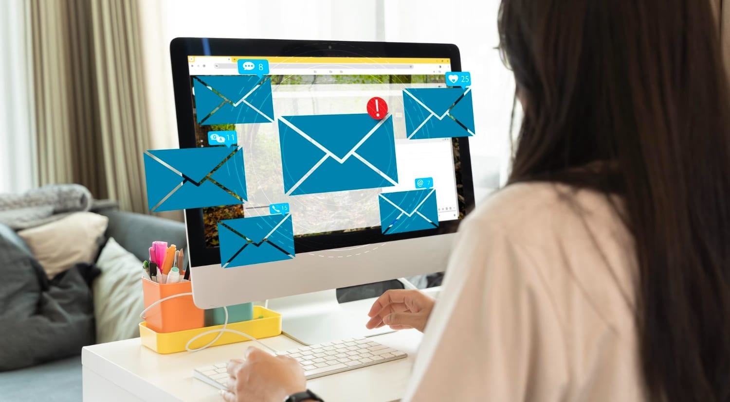 A woman working on a computer with multiple email notifications displayed on the screen, indicating a high volume of unread messages.